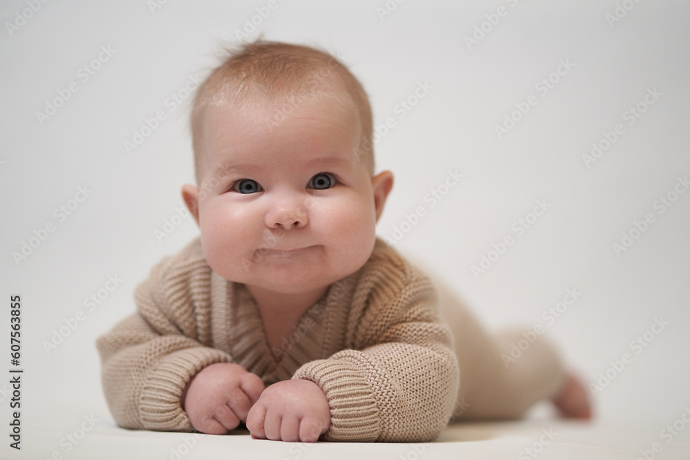 smiling baby in knitted clothes lies on his stomach smiling baby in knitted clothes lies on his stomach