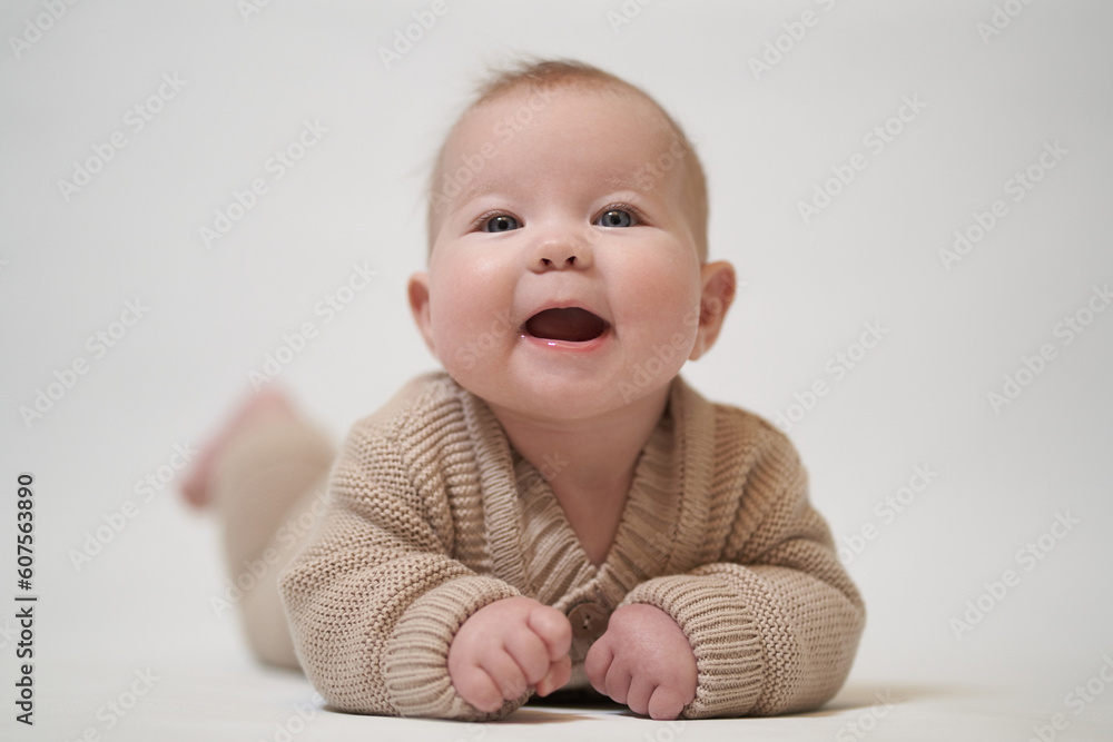 smiling baby in knitted clothes lies on his stomach smiling baby in knitted clothes lies on his stomach