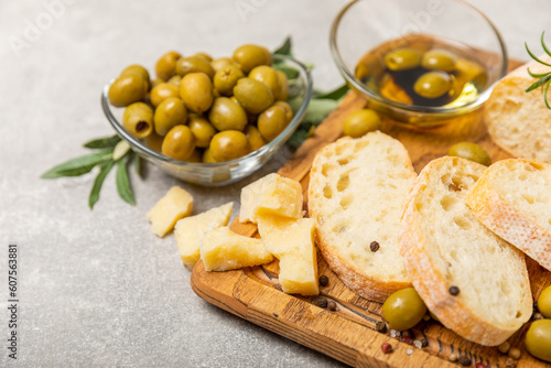 Ciabattas, olive oil in a bowl with olives, herbs, spices, garlic, pesto, parmesan and ciabatta bread on a texture background.Banner. Healthy food concept.Delicacy. Mediterranean Kitchen. Copy space.