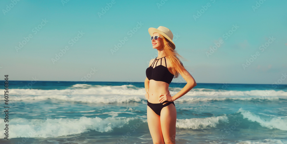 Summer vacation, beautiful happy smiling woman in bikini swimsuit and straw hat on the beach on sea coast with waves background on sunny day Summer vacation, beautiful happy smiling woman in bikini swimsuit and straw hat on the beach on sea coast with waves background on sunny day