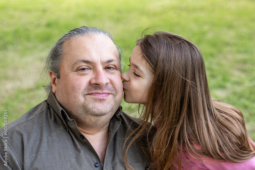Daughter kisses her father in the park. Father's Day. Happy daughter kisses her father. Close-up. Copyspace.