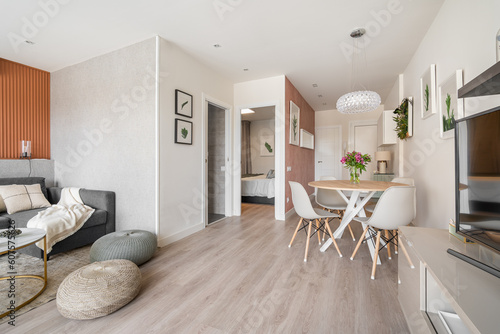 Comfortable seating area with a terracotta color wall with a sofa and poufs near the dining area in the living room studio. Concept of a modern European interior