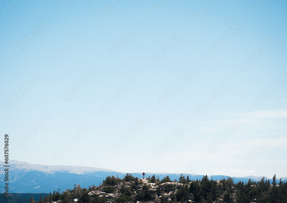 Silueta de persona pequeña en un paisaje de montaña con mucho cielo. Background
