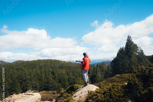 Hombre tocando la guitarra en la montaña. Silueta de persona en el bosque.