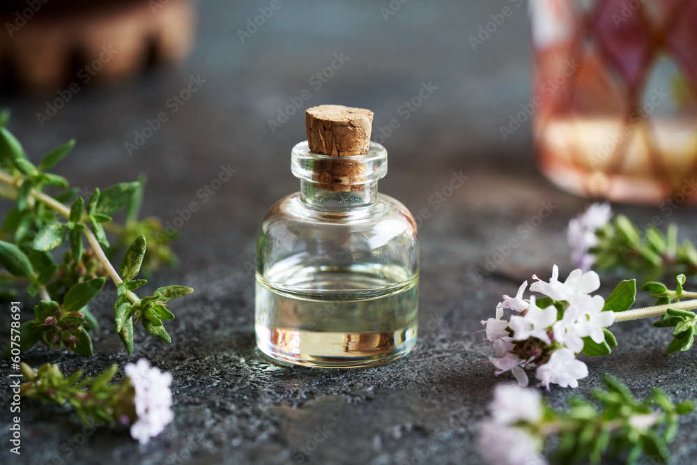 A bottle of thyme essential oil on a dark background A bottle of thyme essential oil on a dark background