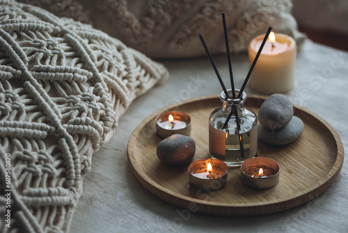 Apartment natural aroma diffusor with sea breeze fragrance. Burning candles on bamboo tray, cozy home atmosphere. Relaxation, detention zone in the living or bedroom. Stones as decor photo