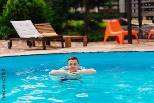 Portrait of a cheerful middle-aged man in the pool with inflatable lifebuoy.