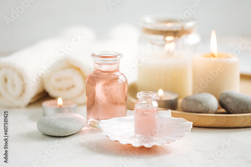 Concept of spa treatment in salon. Natural organic oil  towel  candles as decor. Atmosphere of relax  serenity and pleasure. Anti-stress and detox procedure. Luxury lifestyle. White wooden background