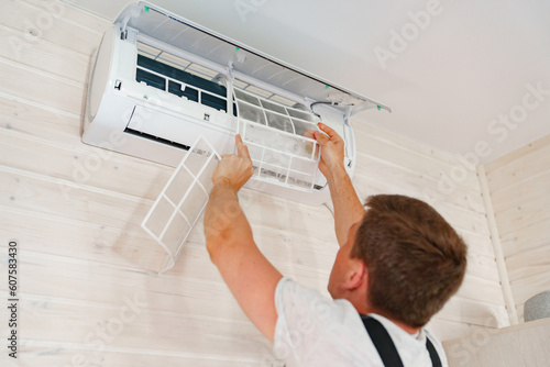Bild auf Leinwand A man replaces and cleans the air cleaner filter from the air conditioner