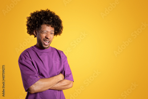 Positive confident mature black curly guy in purple t-shirt with crossed arms on chest