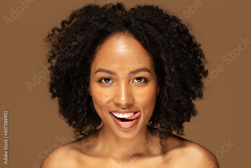 Playful naked black lady posing on brown background, closeup