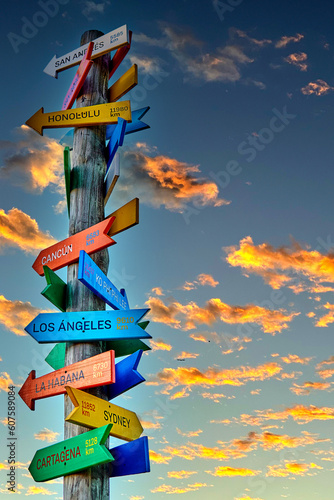 Tourist trunk singpost with colorful signs with distances to the different tourist destinations with a celestial sky with orange clouds in the background. Copy space photo