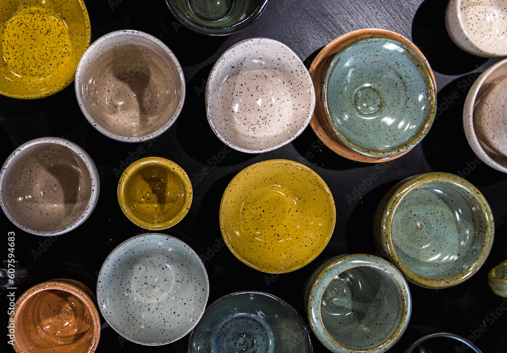 Top view flay lay composition of table full of different colours shapes and sizes handmade speckled pottery ceramics cups bowls