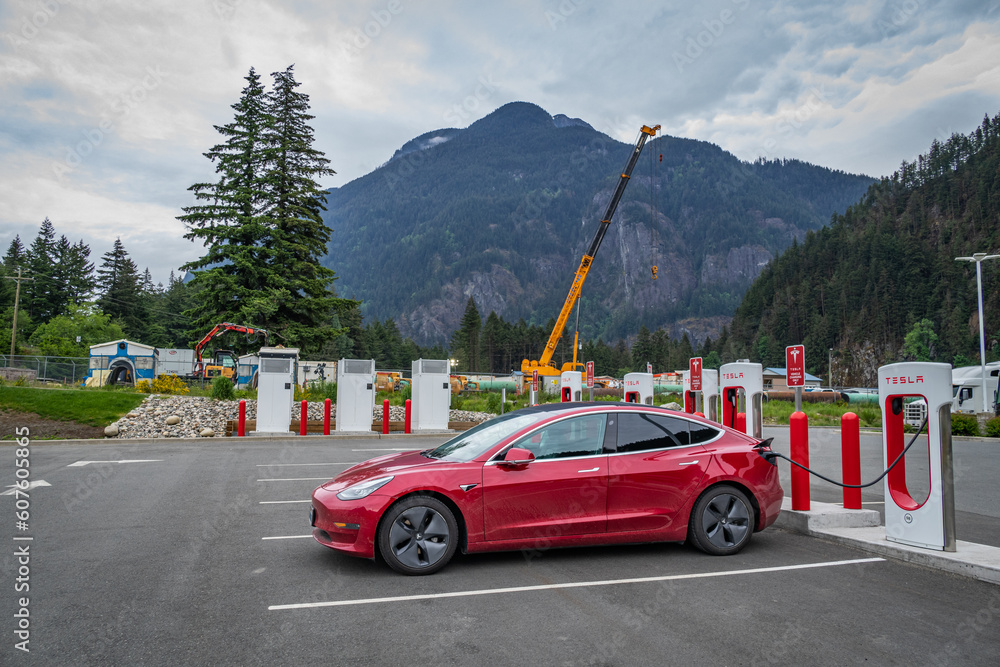 Photo of a red Tesla Model 3 charging at a Tesla supercharger in rural