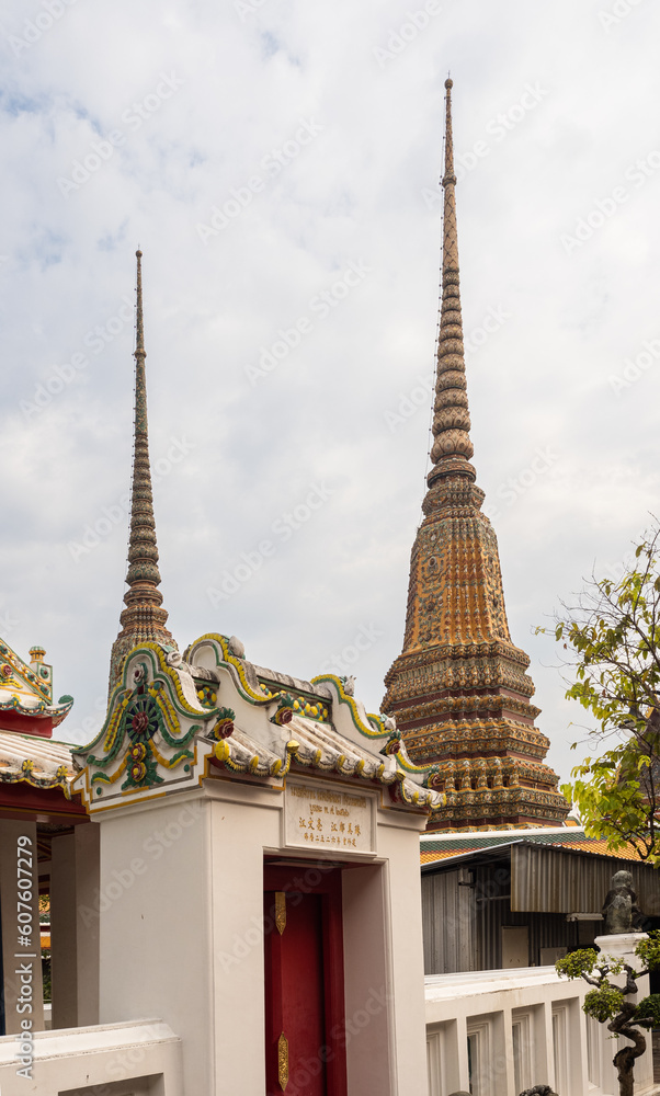 Golden spires and part of the facade raising against the sky at the Wat Pho temple in Bangkok, Thailand.