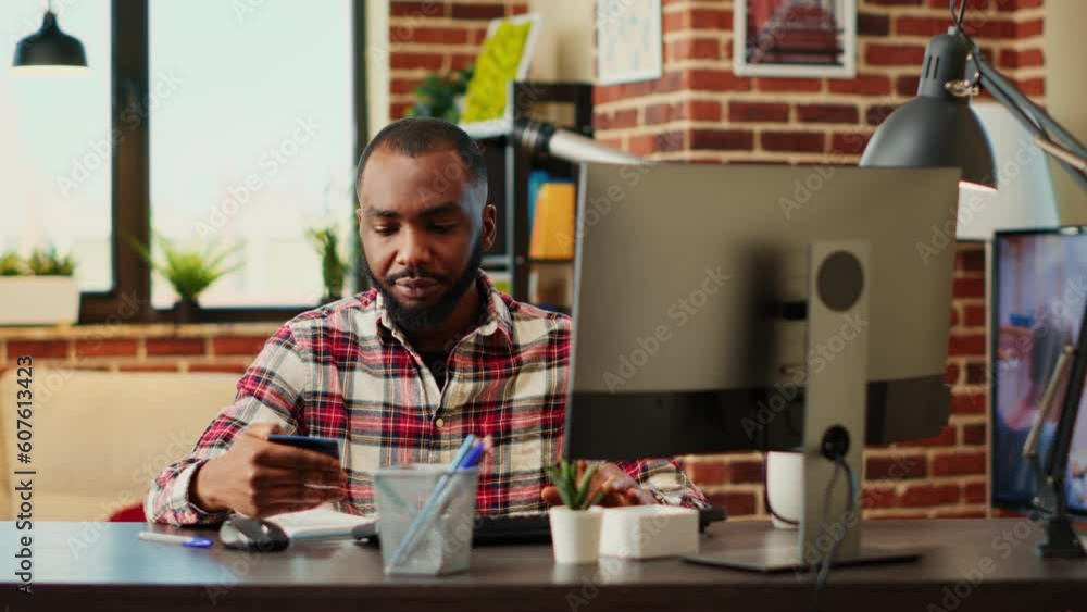 African american man adding payment method on website while in modern stylish apartment living room. Cheerful man excited to do online shopping, carefully typing credit card information African american man adding payment method on website while in modern stylish apartment living room. Cheerful man excited to do online shopping, carefully typing credit card information