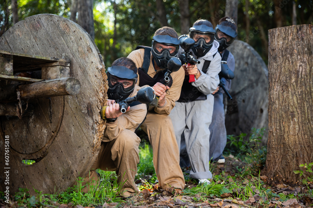 Fototapeta premium Portrait of adult people with guns during paintball game on outdoors arena