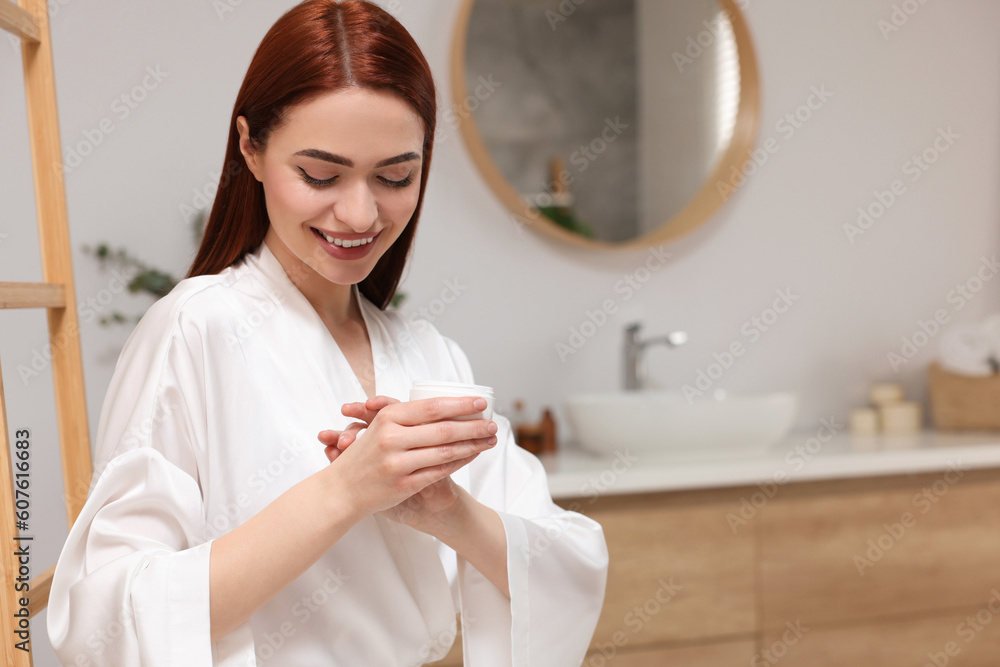 Beautiful young woman applying body cream onto hands in bathroom, space for text Beautiful young woman applying body cream onto hands in bathroom, space for text