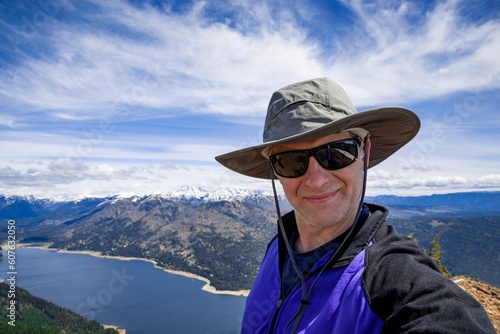 Adventurous athletic male hiker taking a selfie with a large lake and mountains in the background in the Pacific Northwest.  © Pelo Blanco Photo
