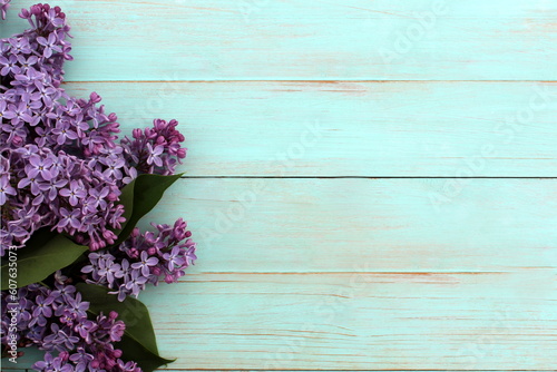 Purple lilac flowers lie on a green painted wooden surface.