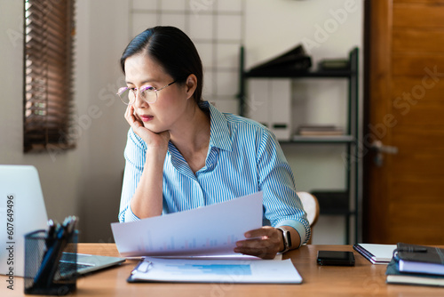 Close up of businesswoman hold business document while thinking strategy and reading data on laptop