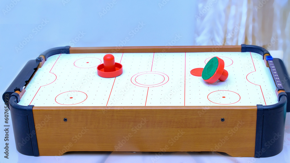 Stockfoto med beskrivningen The plot shot of an air hockey game on a table  Portable table hockey includes plastic hockey blades, a mini puck and  goalkeepers | Adobe Stock