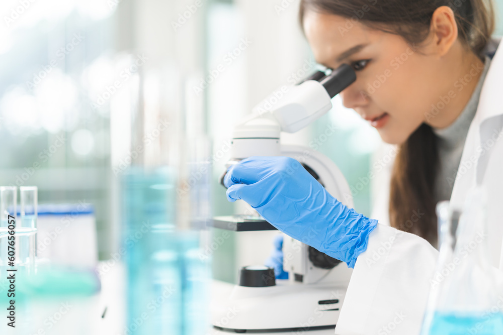 Fototapeta premium Medical development research laboratory, science young woman scientist hand in glove looking under microscope for test analysis samples in lab. Microbiology, analysing biochemicals for medicine.