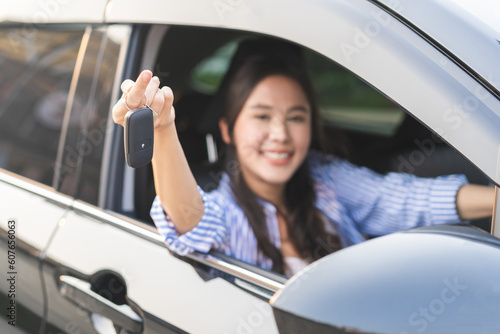 Dealership automobile, smile asian young woman, happy girl sitting in new car after purchase success, showing, holding auto remote key of vehicle, owner driver female buy gift for yourself at showroom