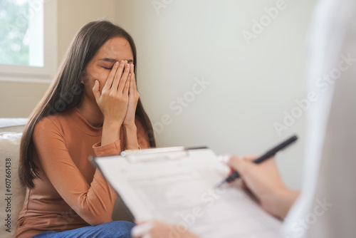 Psychology, depression. Sad, suffering asian young woman, girl consulting with psychologist, psychiatrist while patient counseling mental with doctor hand taking notes at clinic. Encouraging, therapy. photo