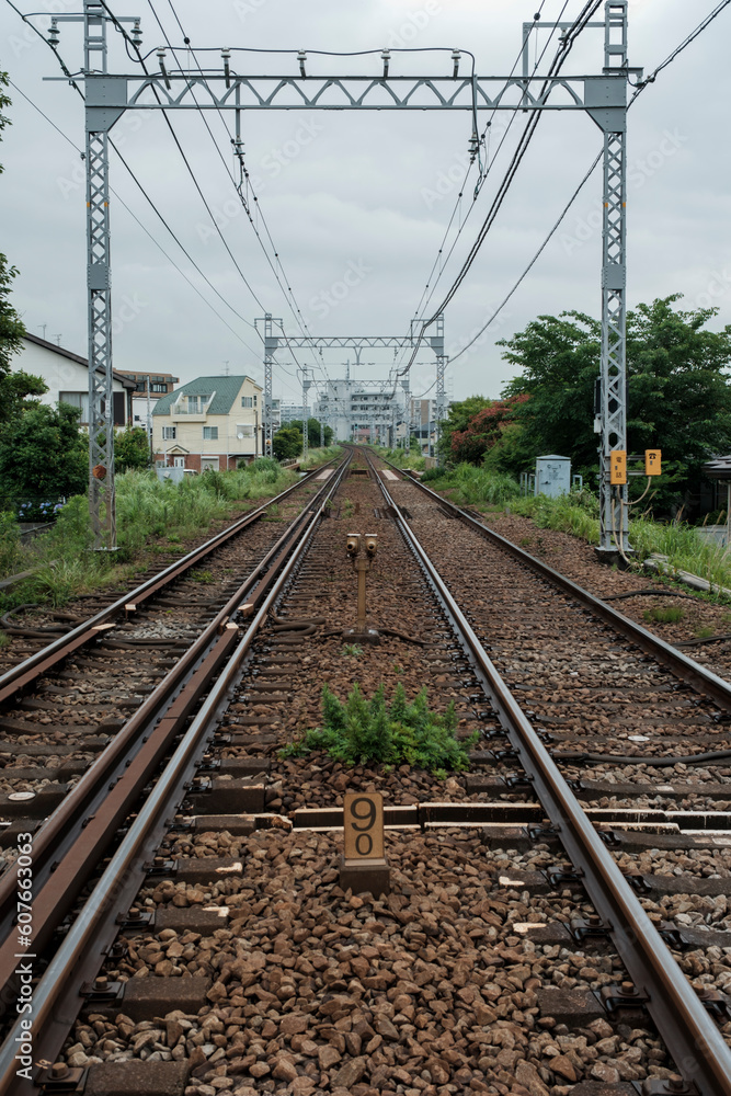 雨の日の駅、曇り空の下に伸びた直線の線路 道のり・進路のイメージ