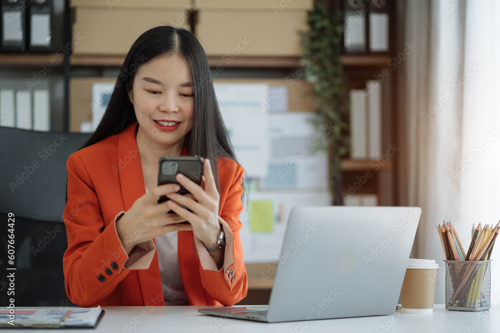 Asian woman talking mobile phone and working on laptop and calculator on table in office. Asian woman talking mobile phone and working on laptop and calculator on table in office.