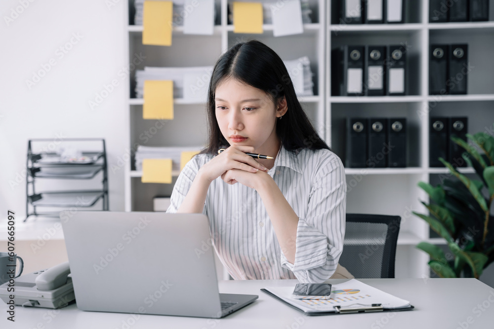 business woman sitting at her desk, reading stats and graphs on paperwork at the office. business woman sitting at her desk, reading stats and graphs on paperwork at the office.