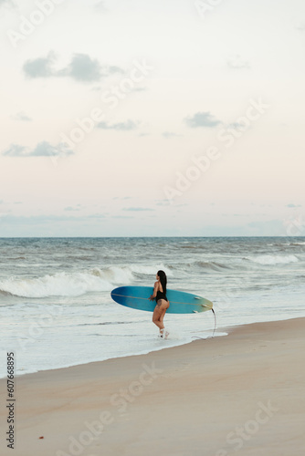 woman with surfboard on beach