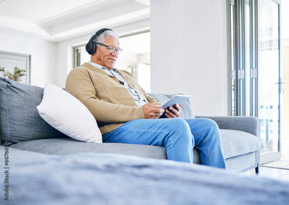 Elderly man, relax with tablet and headphones at home, retirement and technology with online streaming. Surfing internet, watching videos and wireless tech with old male person sitting on couch Elderly man, relax with tablet and headphones at home, retirement and technology with online streaming. Surfing internet, watching videos and wireless tech with old male person sitting on couch