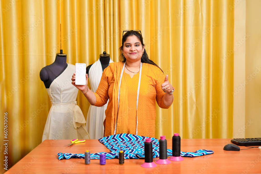 Young indian female fashion designer showing smartphone screen. Young indian female fashion designer showing smartphone screen.