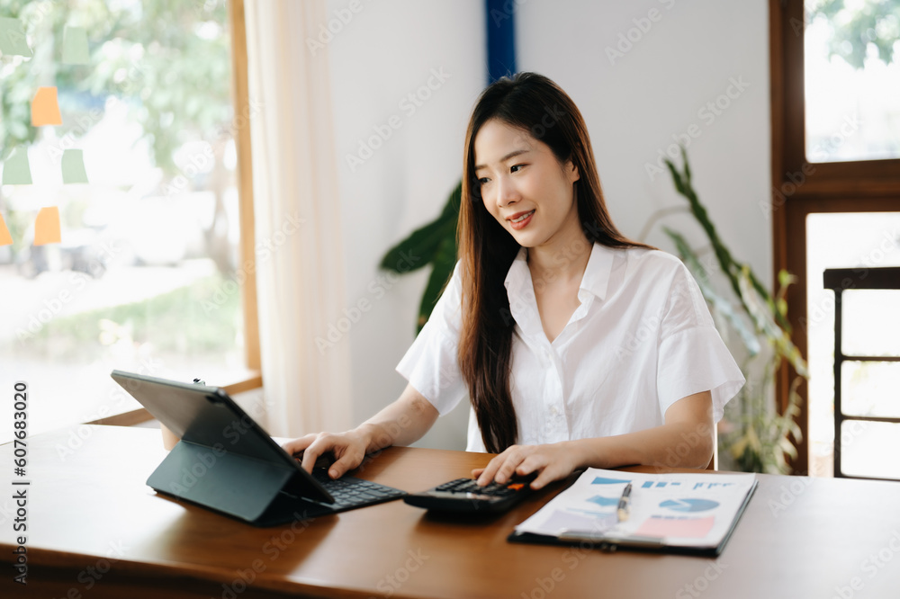 Asian woman working in the office with working notepad, tablet and laptop documents Asian woman working in the office with working notepad, tablet and laptop documents