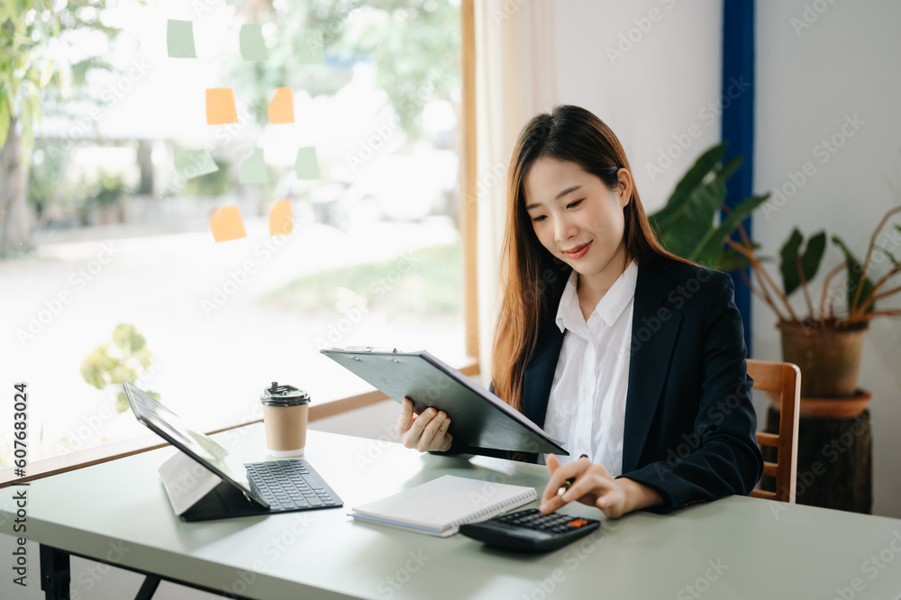 Beautiful Asian business woman typing laptop and tablet Placed at the table at the office.. Beautiful Asian business woman typing laptop and tablet Placed at the table at the office..