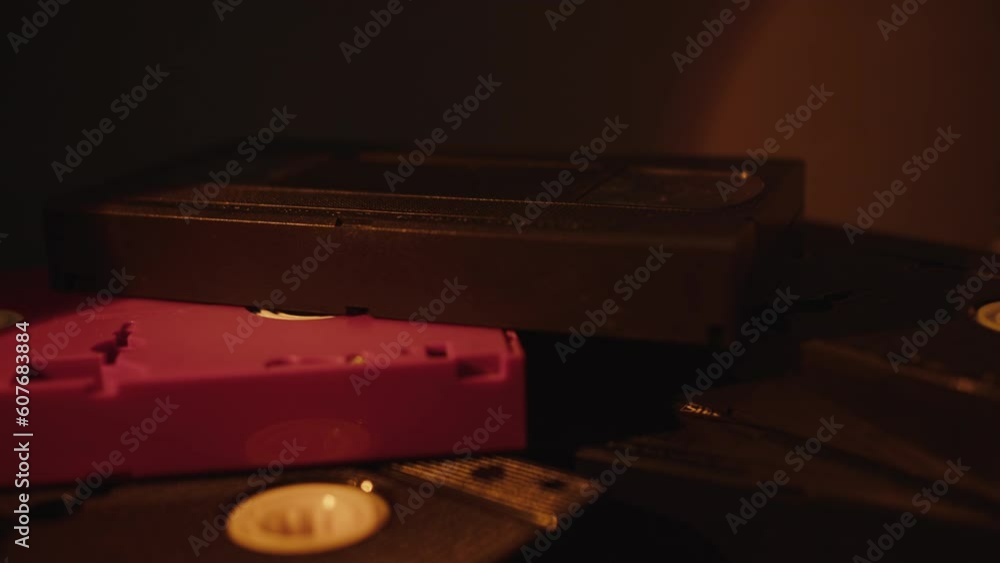 a stack of VHS cassettes stand randomly in the light of a night lamp a stack of VHS cassettes stand randomly in the light of a night lamp