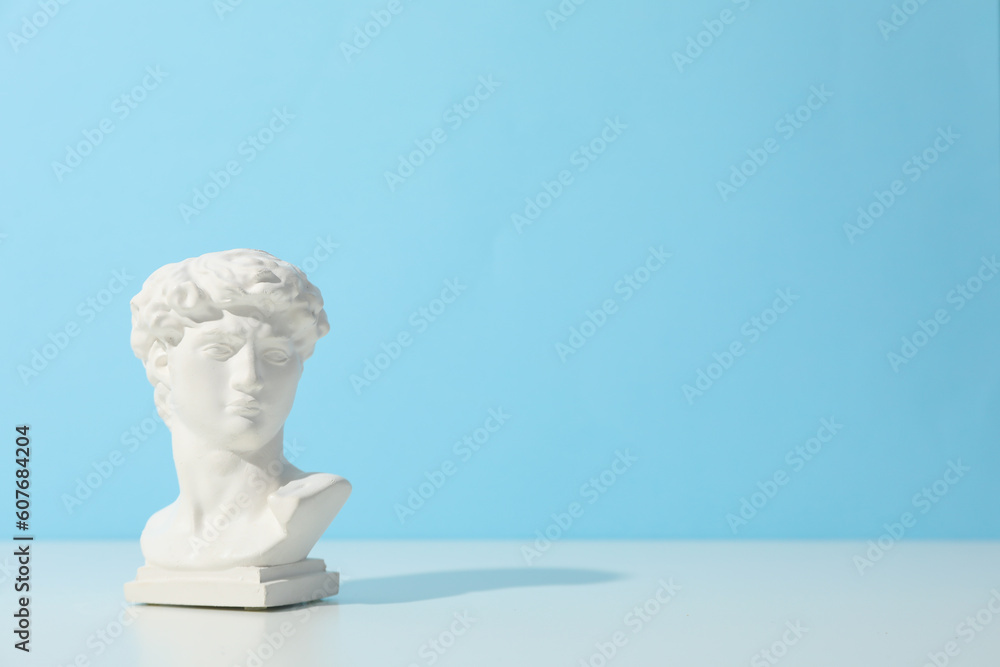 Ancient head on white table against blue background Ancient head on white table against blue background