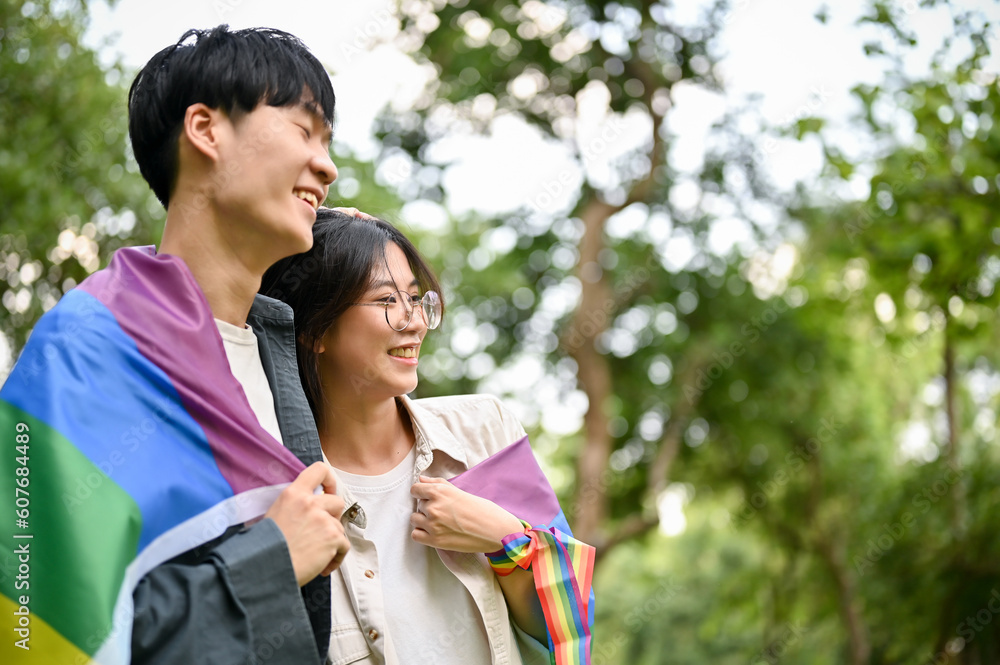 Happy young Asian couple gently loving and hugging with the LGBT rainbow flag Happy young Asian couple gently loving and hugging with the LGBT rainbow flag