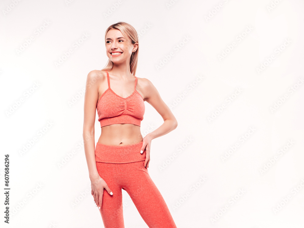 Young beautiful smiling blond female in pink sports clothing costume . Sexy carefree woman posing on white background in studio. Positive model having fun indoors. Cheerful and happy. Very slim