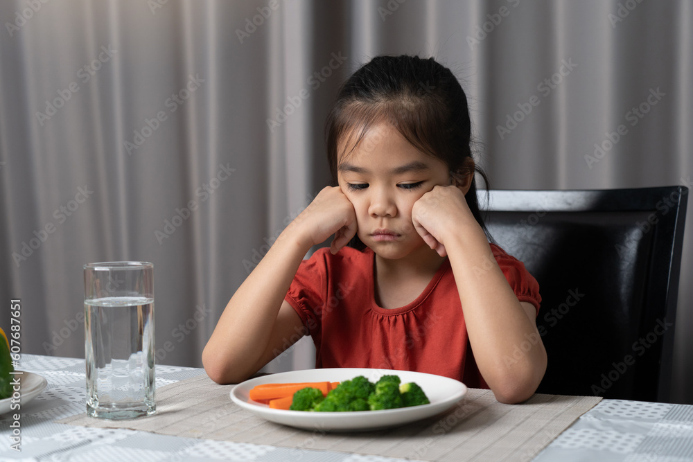 Little cute kid girl refusing to eat healthy vegetables. Children do not like to eat vegetables.