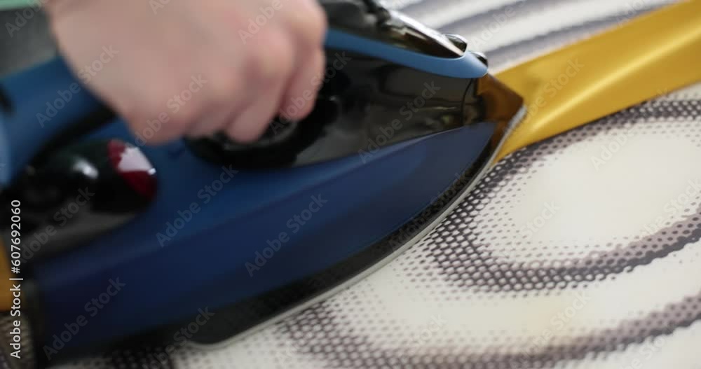 Housewife irons yellow belt with hot steam. Woman taking care of clothes at home Housewife irons yellow belt with hot steam. Woman taking care of clothes at home
