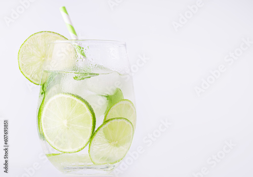 Summer lemonade with basil and lime on white background. One fresh summer cocktail with basil, green lemon and ice cubes. Drink concept