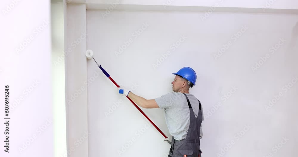 ainter in helmet paints wall with roller. Painting and repair and home improvement ainter in helmet paints wall with roller. Painting and repair and home improvement