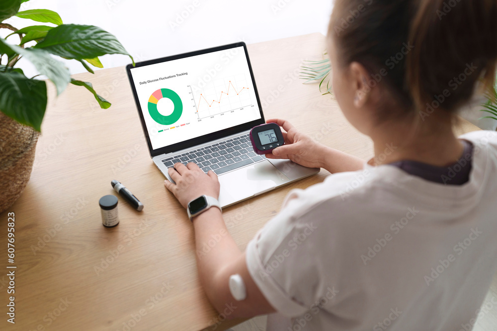 Woman with diabetes synchronizing laptop and glucometer at home Woman with diabetes synchronizing laptop and glucometer at home