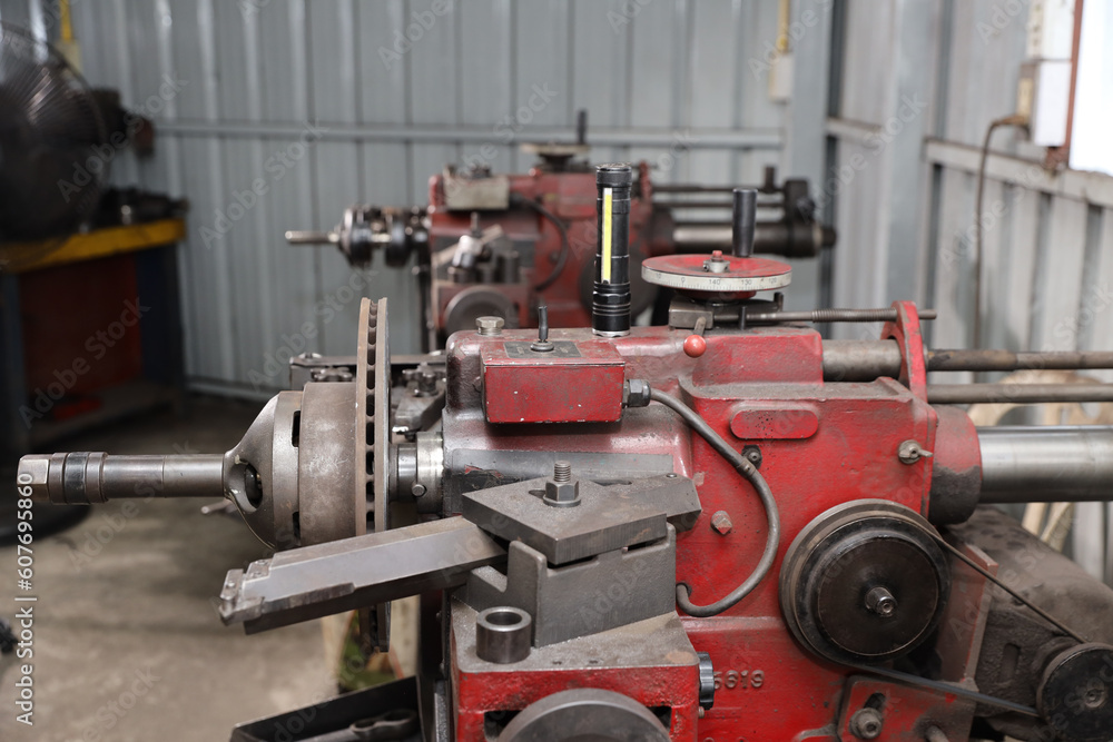 Close up metal lathe machine for polishing car disc brake at garage. Maintenance automotive and inspecting vehicle part concept Close up metal lathe machine for polishing car disc brake at garage. Maintenance automotive and inspecting vehicle part concept