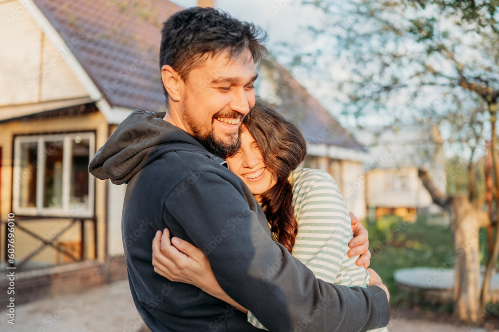 Cheerful couple embracing in front yard with house in background Cheerful couple embracing in front yard with house in background