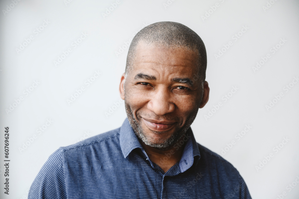 Smiling mature man with shaved head in front of white wall Smiling mature man with shaved head in front of white wall