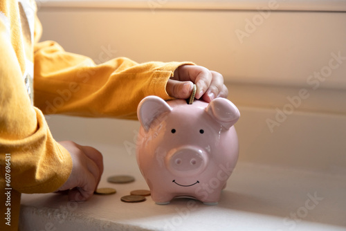Boy saving money in piggy bank photo